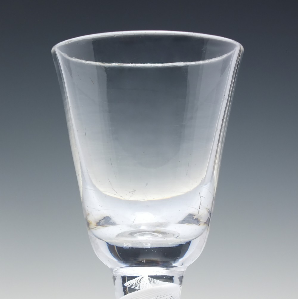 A clear Georgian lead glass wine glass featuring an internal white opaque twist stem and a stepped helmet foot. View IV