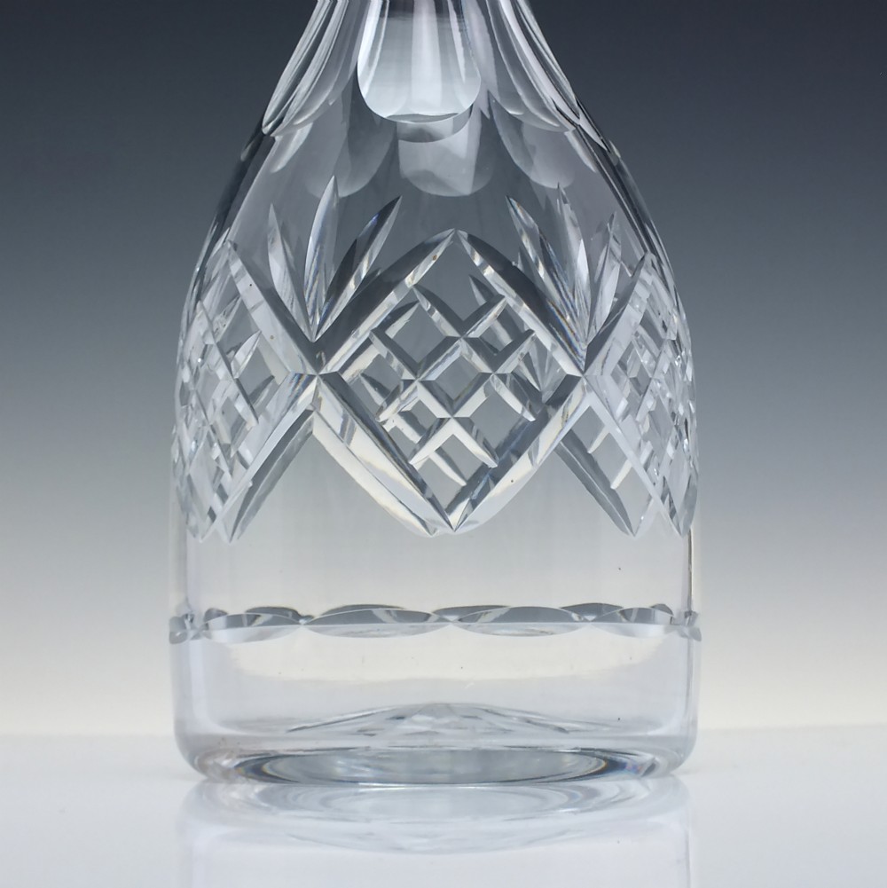 A clear cut crystal glass decanter with a geometric diamond cut body, smooth neck, and faceted glass stopper. View III