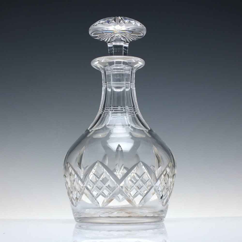 A clear cut lead crystal spirit decanter featuring a geometric diamond-cut lower body and a matching faceted glass stopper. View II