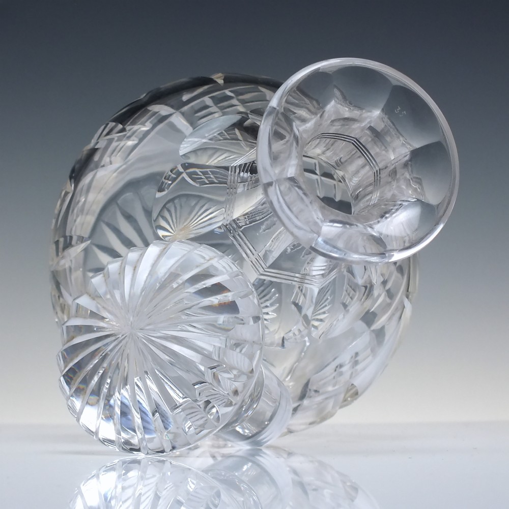 A clear cut lead crystal spirit decanter featuring a geometric diamond-cut lower body and a matching faceted glass stopper. View IV
