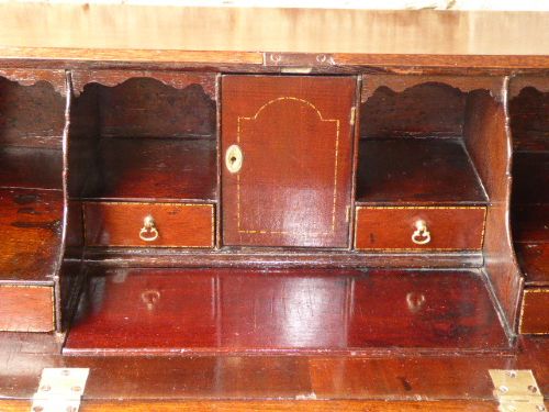 An eighteenth-century Georgian dark mahogany writing bureau with an open slant lid showing interior pigeonholes above three drawers with brass hardware. View V