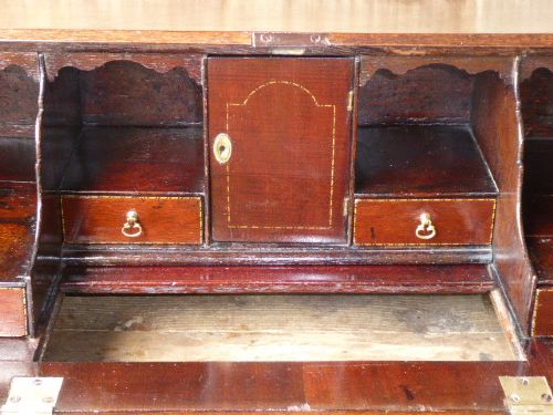 An eighteenth-century Georgian dark mahogany writing bureau with an open slant lid showing interior pigeonholes above three drawers with brass hardware. View VI