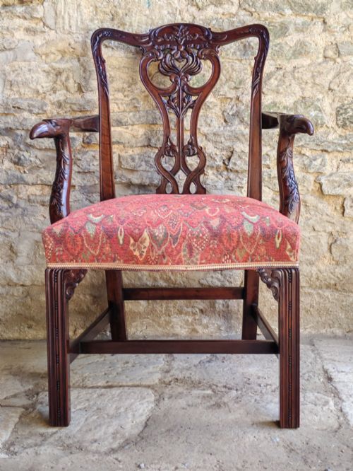 fig 1. A dark mahogany Chippendale revival carver armchair with an intricately carved splat back and red patterned fabric seat cushion.