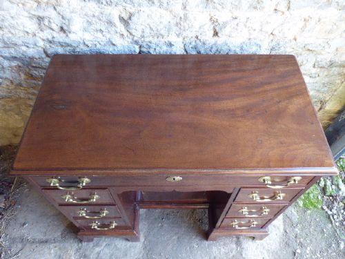 An antique Georgian mahogany kneehole desk featuring brass swan-neck handles, a central recessed cupboard, and bracket feet. View II