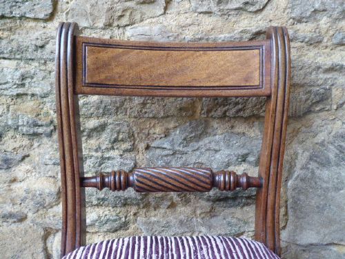 A set of four Regency mahogany dining chairs featuring carved rope-twist cross rails, reeded uprights, turned front legs, and plum striped upholstered seats. View IV