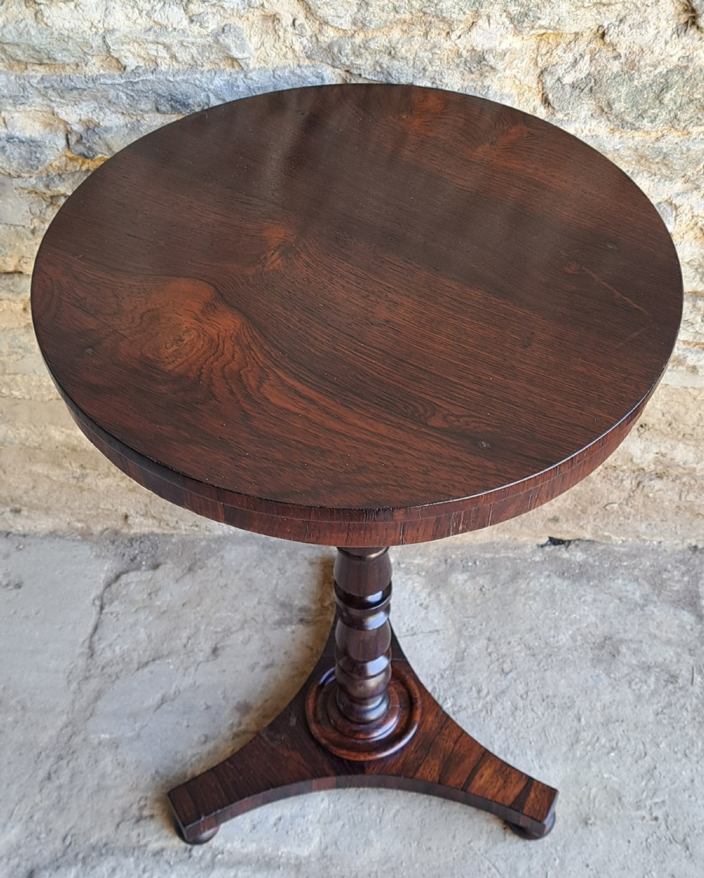 An antique round rosewood wine table featuring a turned pedestal column and a tripod base. View II