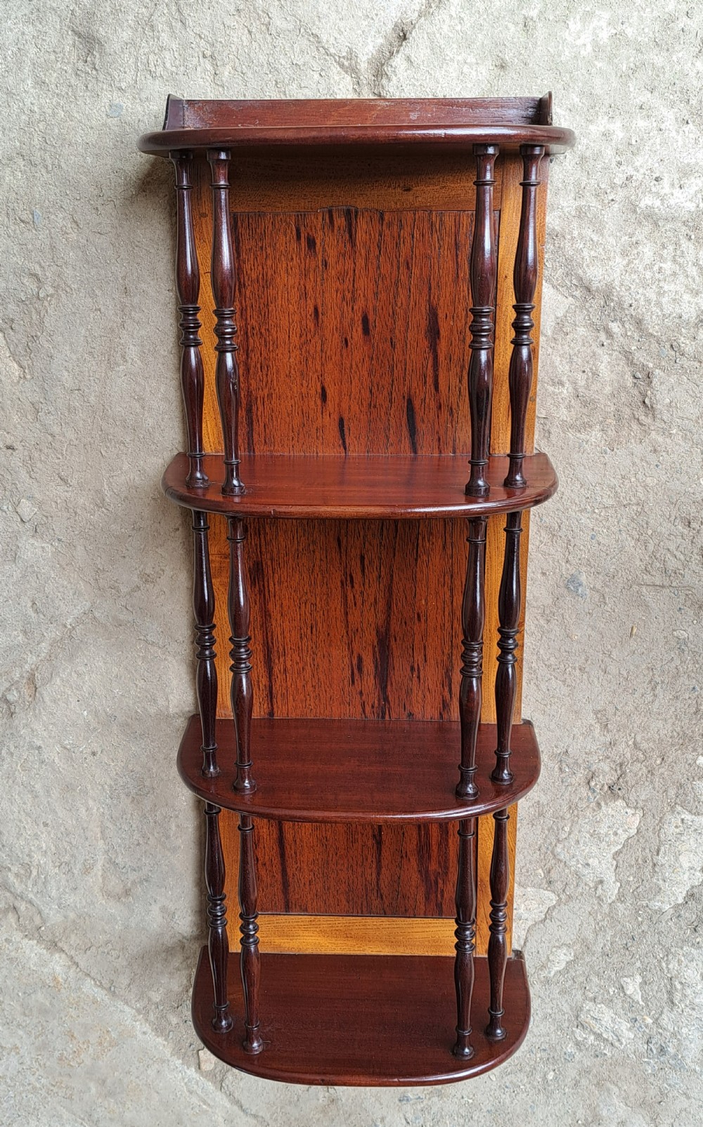 A four-tier dark mahogany hanging wall shelf unit featuring slender turned spindle supports and a timber backboard.