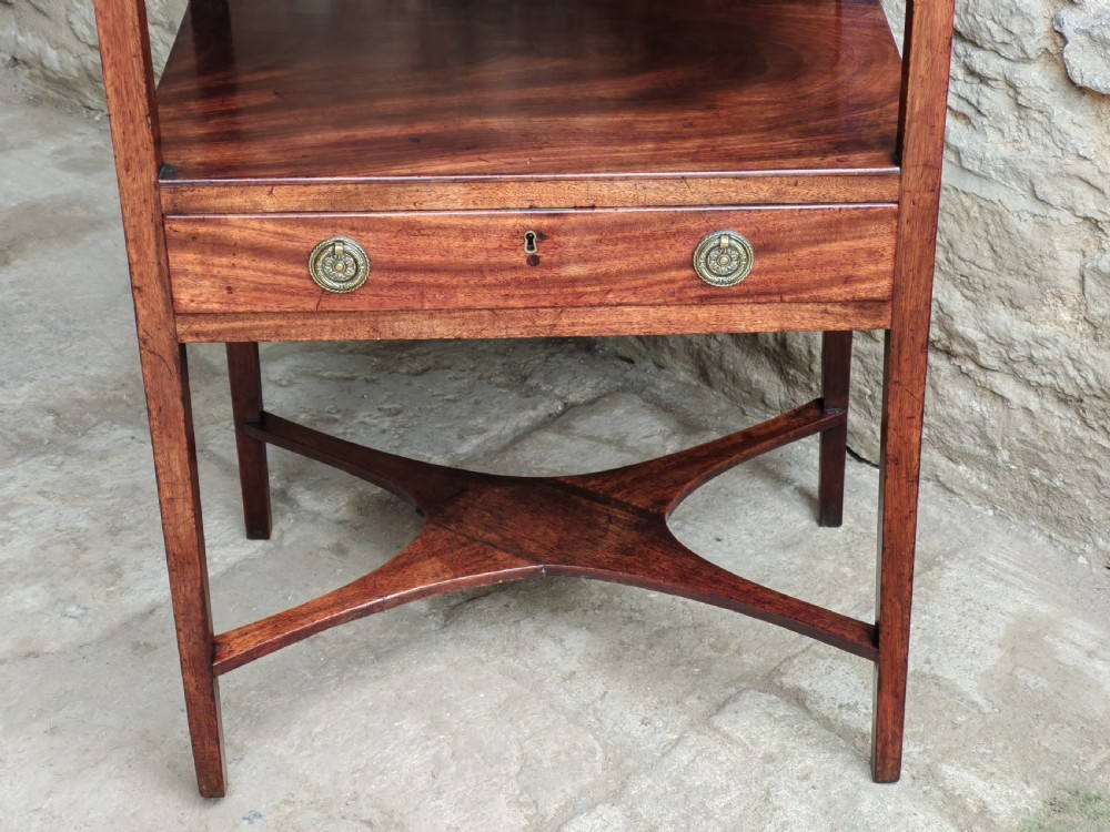 A Georgian mahogany bedside stand featuring a gallery back shelf, an open middle compartment, a single drawer with brass ring handles, and tapered legs joined by a cross-stretcher. View IV