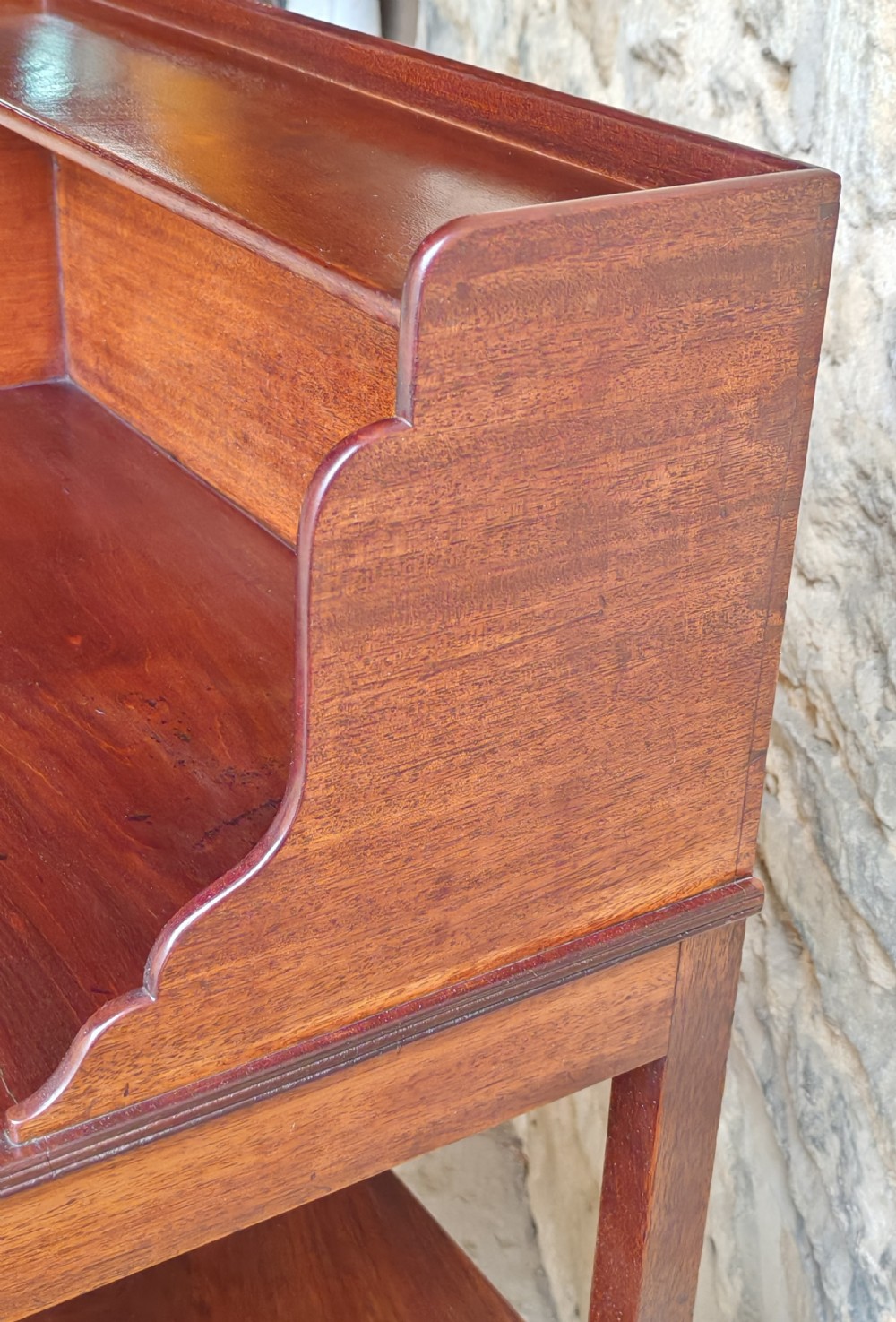 A Georgian mahogany bedside stand featuring a gallery back shelf, an open middle compartment, a single drawer with brass ring handles, and tapered legs joined by a cross-stretcher. View VI