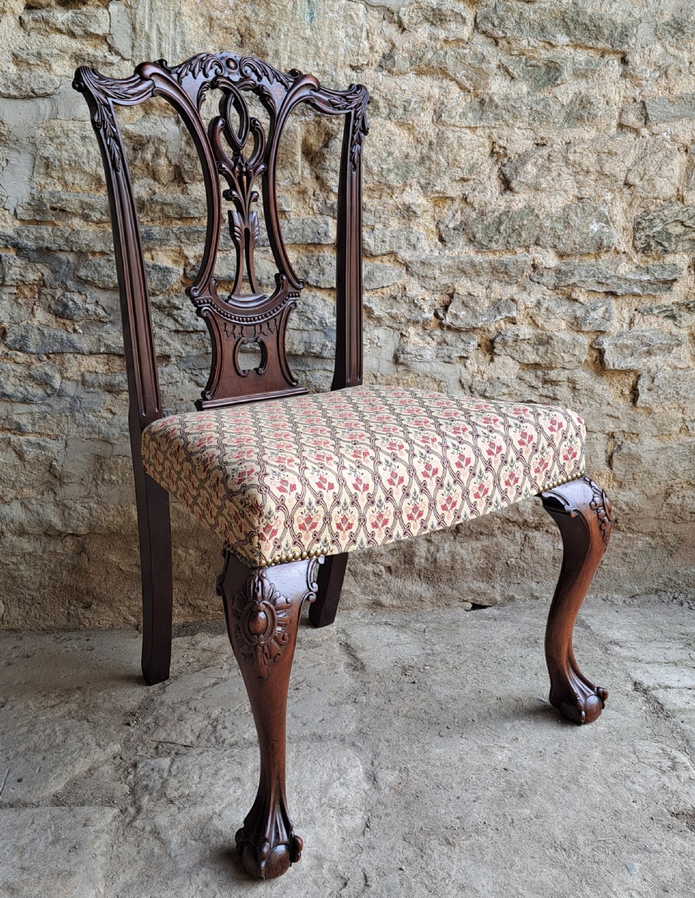 A mid-19th-century mahogany Chippendale style side chair featuring a carved pierced splat back, patterned upholstery, and cabriole front legs with ball-and-claw feet.