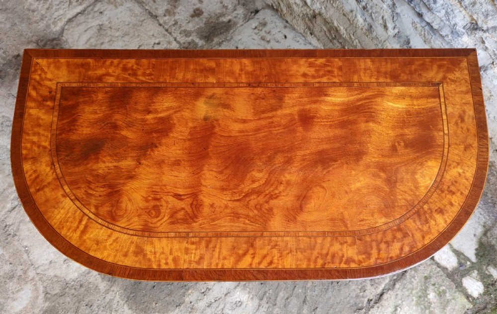 A late eighteenth-century Georgian satinwood demi-lune card table featuring inlaid crossbanding and four square tapered legs. View II