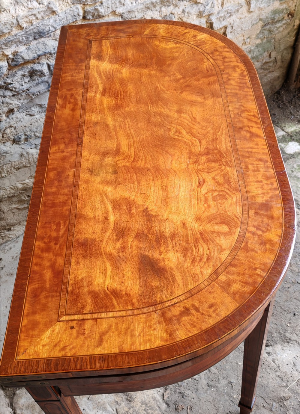 A late eighteenth-century Georgian satinwood demi-lune card table featuring inlaid crossbanding and four square tapered legs. View III