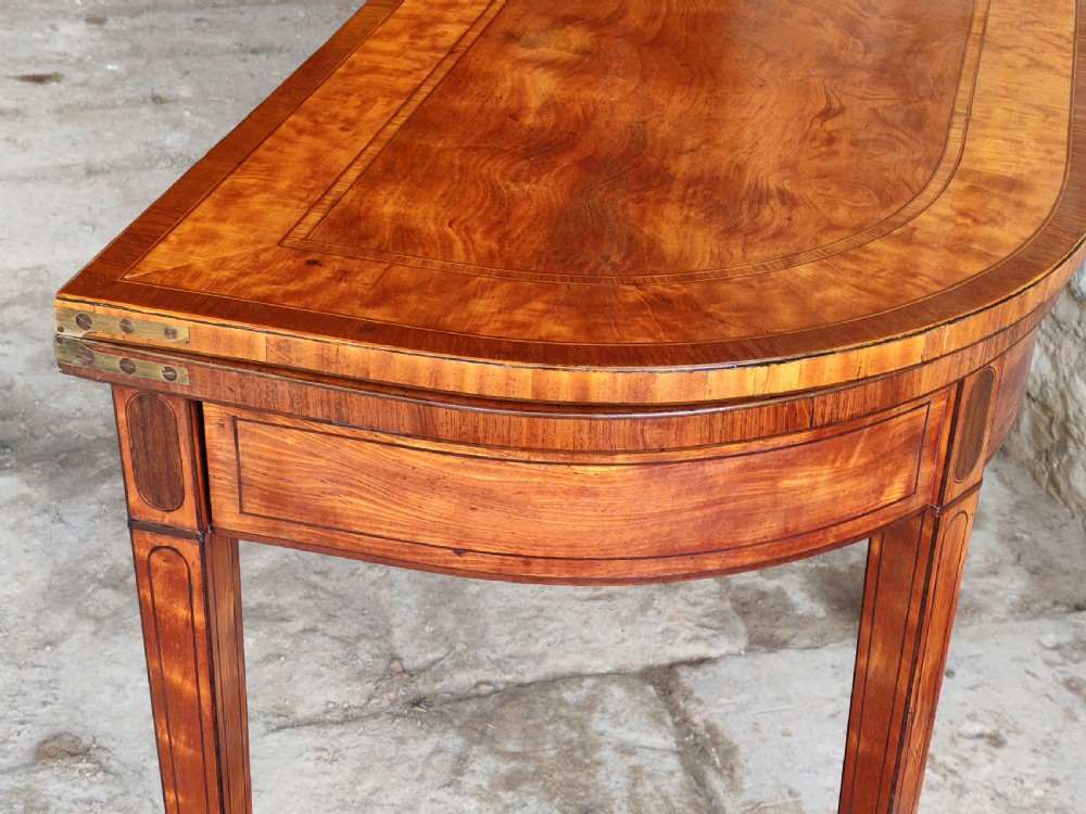 A late eighteenth-century Georgian satinwood demi-lune card table featuring inlaid crossbanding and four square tapered legs. View V