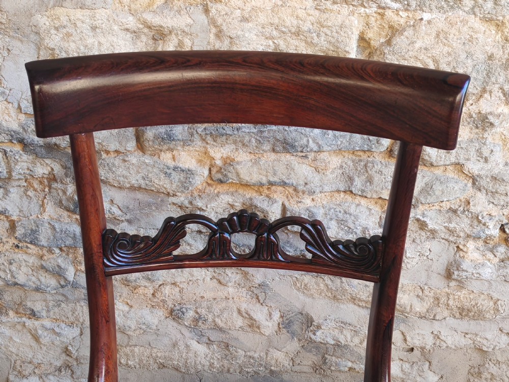 A pair of circa 1830 rosewood dining chairs featuring carved back splats, woven cane seats, and reeded front legs. View III