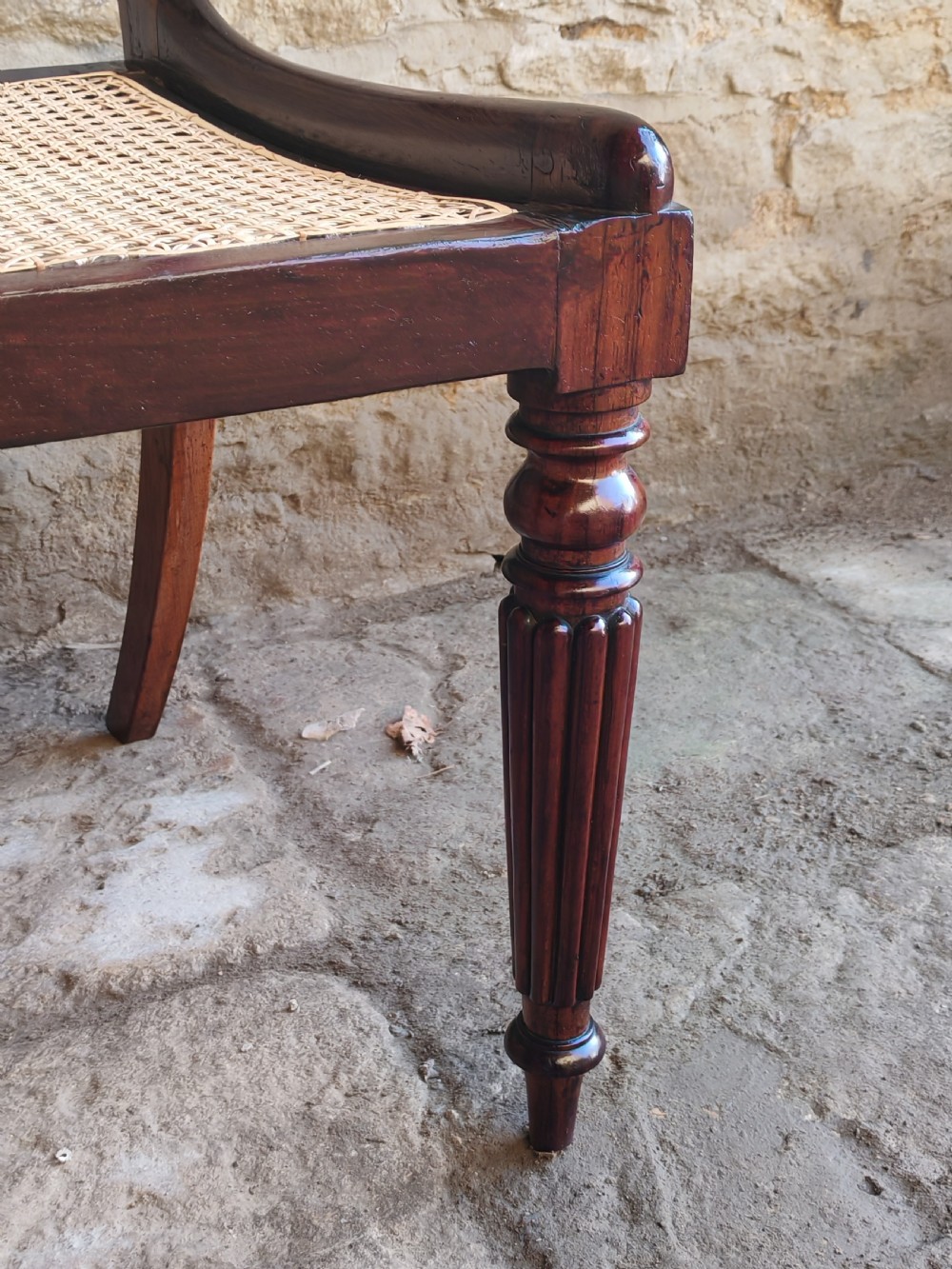 A pair of circa 1830 rosewood dining chairs featuring carved back splats, woven cane seats, and reeded front legs. View V