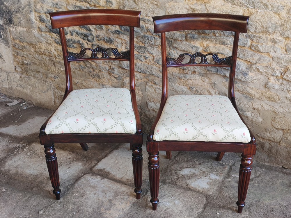 A pair of circa 1830 rosewood dining chairs featuring carved back splats, woven cane seats, and reeded front legs. View VII