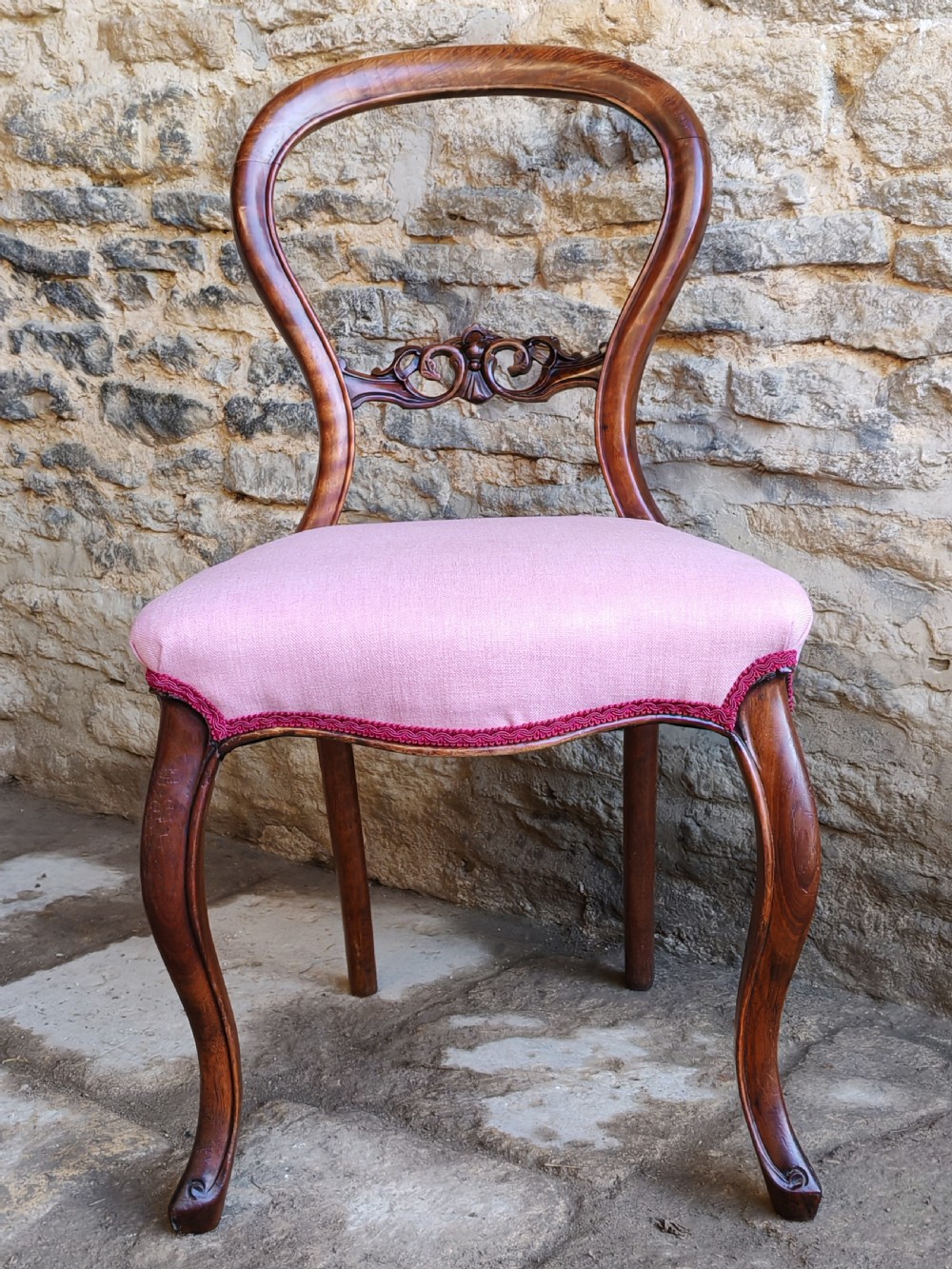 A set of four late Victorian walnut dining chairs featuring balloon backs, carved central splats, cabriole front legs, and pink upholstered seats. View II