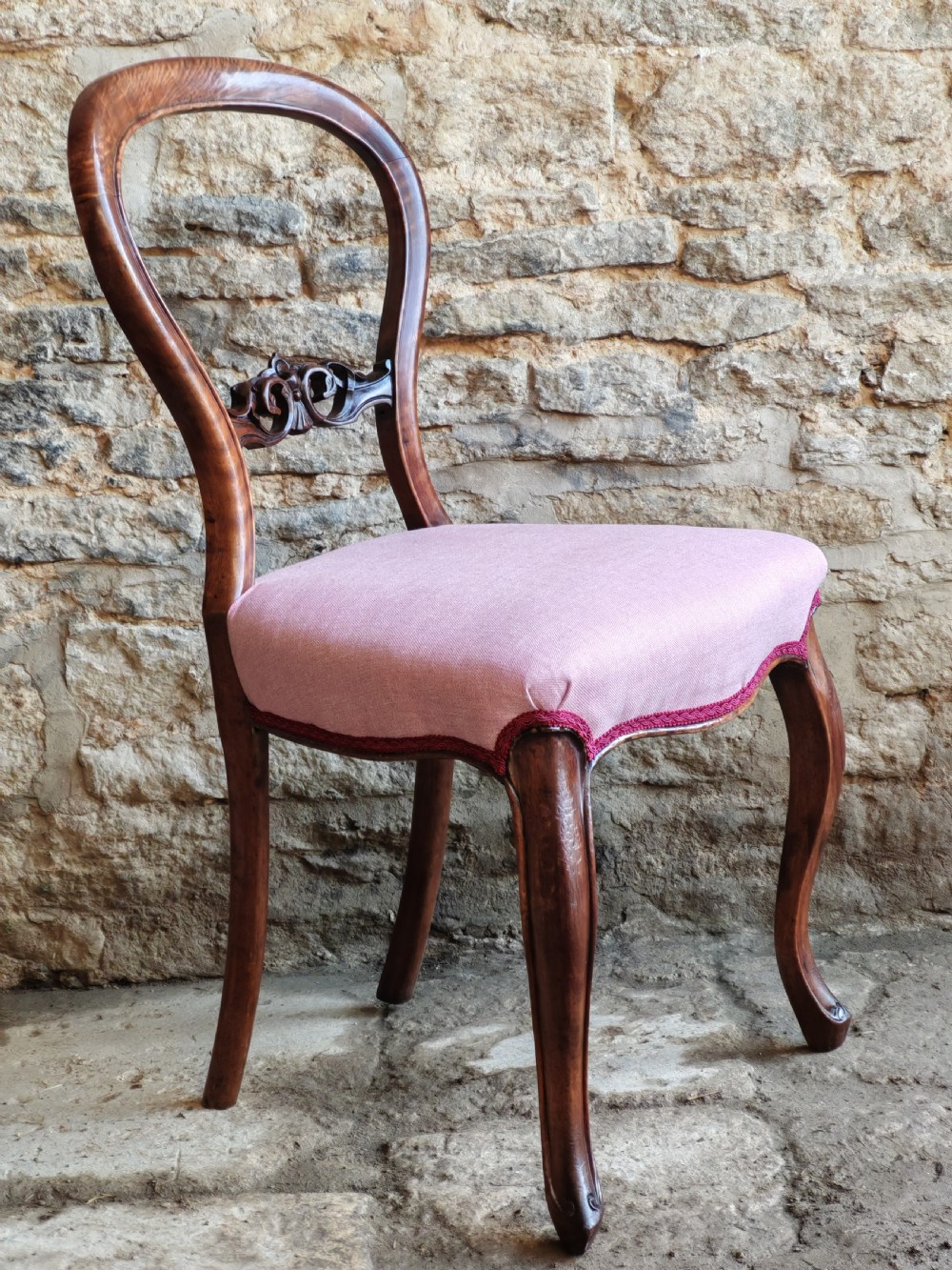 A set of four late Victorian walnut dining chairs featuring balloon backs, carved central splats, cabriole front legs, and pink upholstered seats. View III