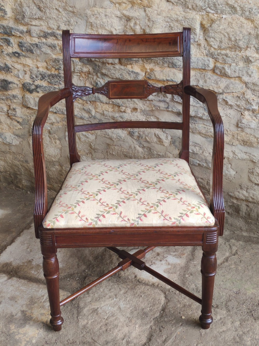 A Georgian mahogany carver armchair featuring reeded arms, a central carved splat, an upholstered seat, turned front legs, and an X-frame stretcher. View II
