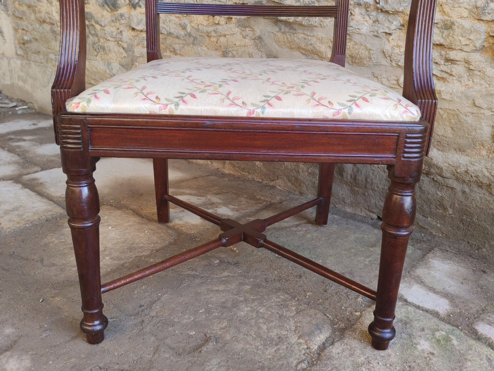 A Georgian mahogany carver armchair featuring reeded arms, a central carved splat, an upholstered seat, turned front legs, and an X-frame stretcher. View VI