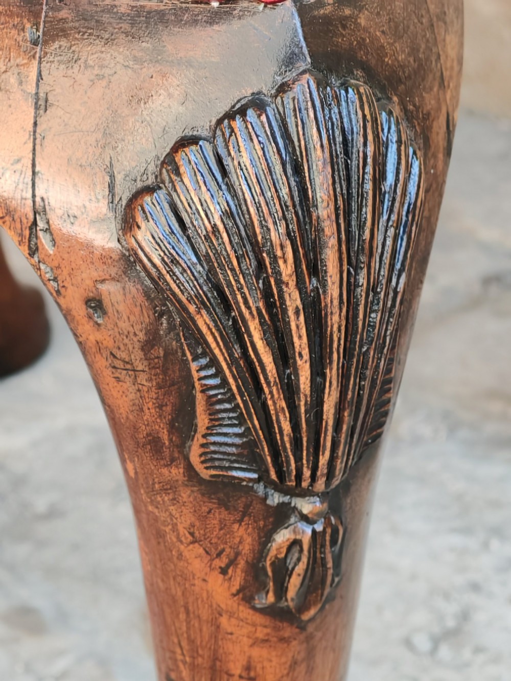 A rectangular 19th-century walnut stool featuring cabriole legs with carved shell details and a light green patterned fabric seat edged with red braid trim. View V