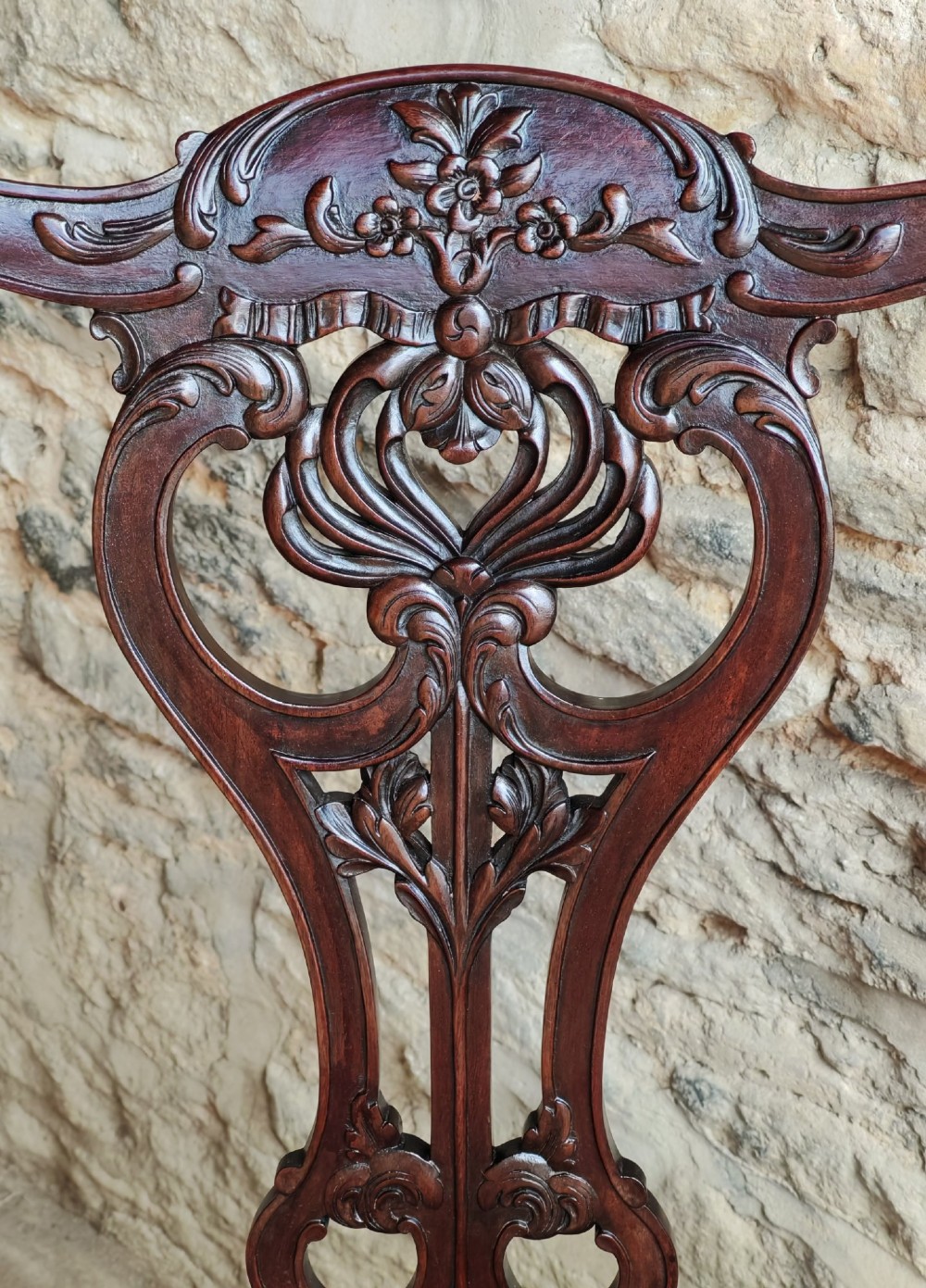 An antique dark mahogany carver armchair with a carved pierced splat back, eagle head armrests, patterned red upholstered seat, and square legs with an H-stretcher. View V