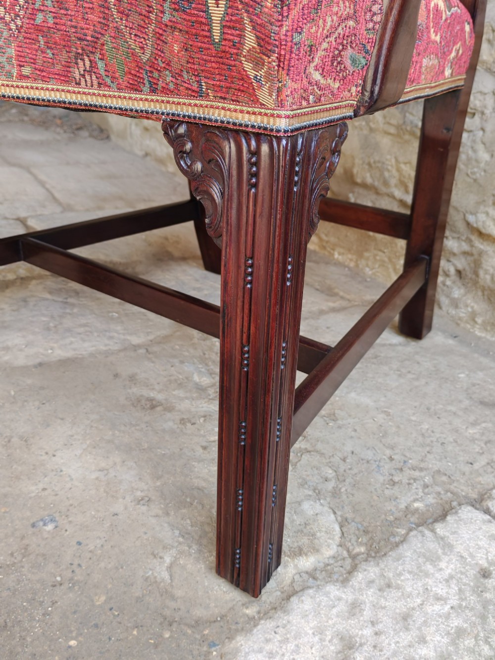 An antique dark mahogany carver armchair with a carved pierced splat back, eagle head armrests, patterned red upholstered seat, and square legs with an H-stretcher. View IX