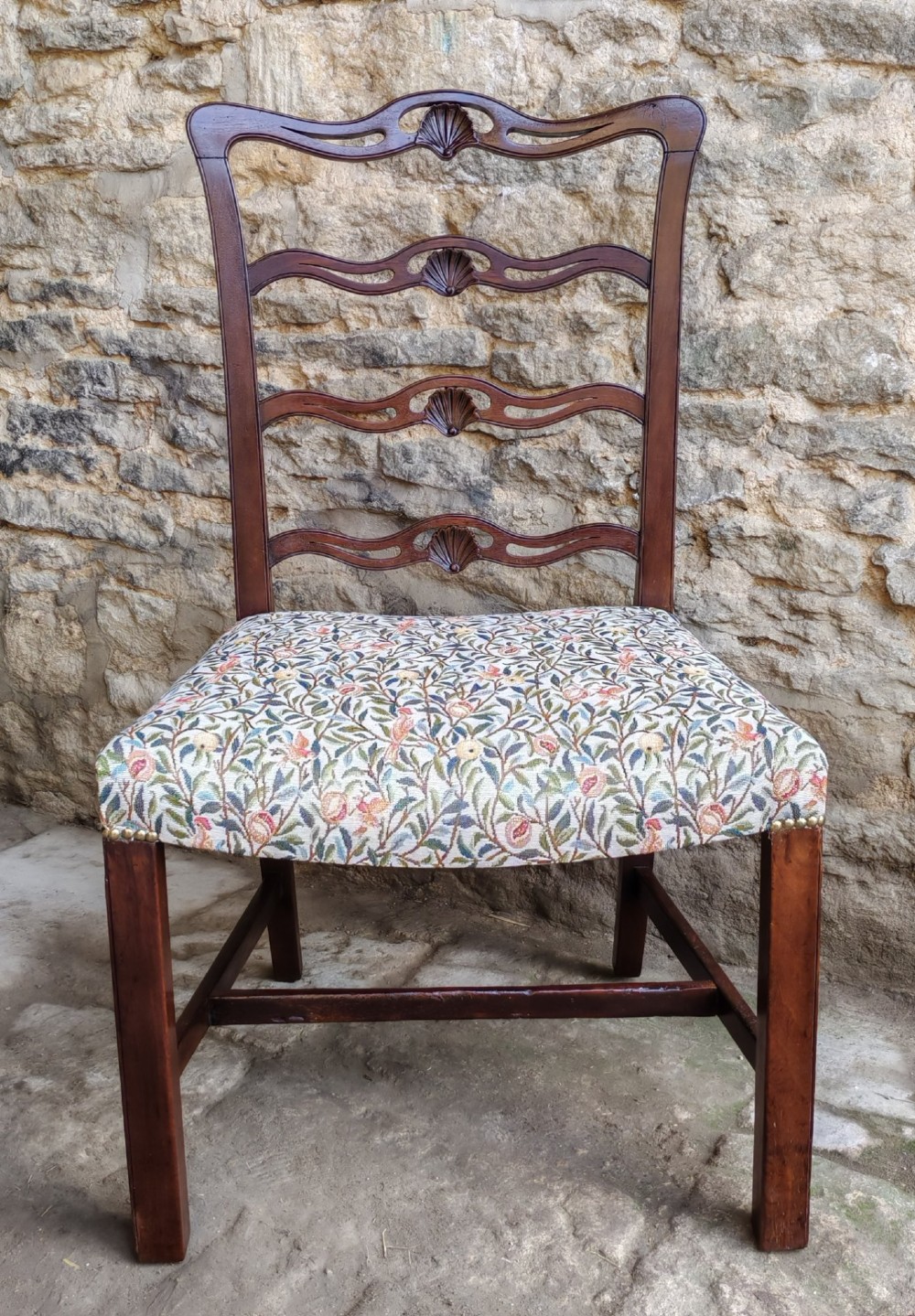 A Victorian mahogany ladderback side chair featuring four carved shell motifs on the back rails and a floral tapestry drop-in seat.