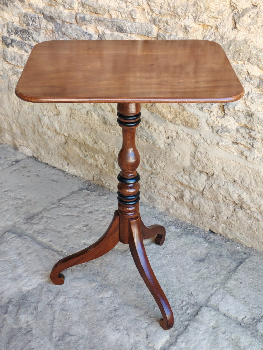 A Regency yew wood tripod table featuring a rectangular top with rounded corners, a turned central column with ebonised rings, and three splayed legs.