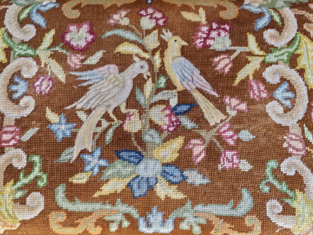 An antique walnut footstool with cabriole legs featuring a brown needlepoint upholstered seat depicting two birds amidst flowers. View II