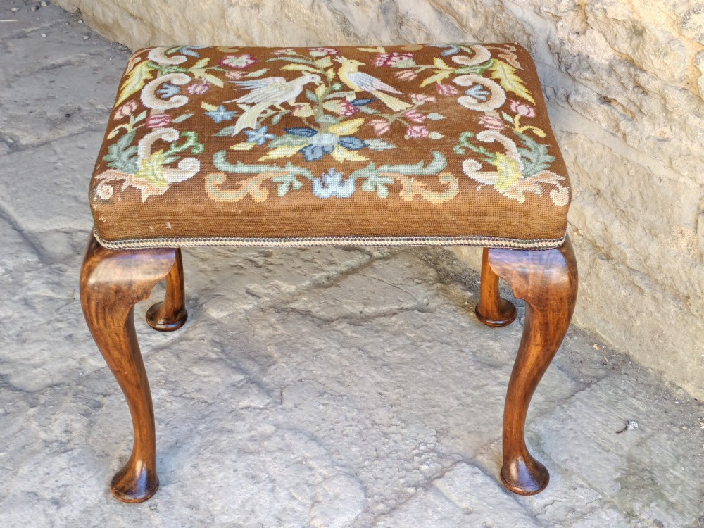 An antique walnut footstool with cabriole legs featuring a brown needlepoint upholstered seat depicting two birds amidst flowers. View III