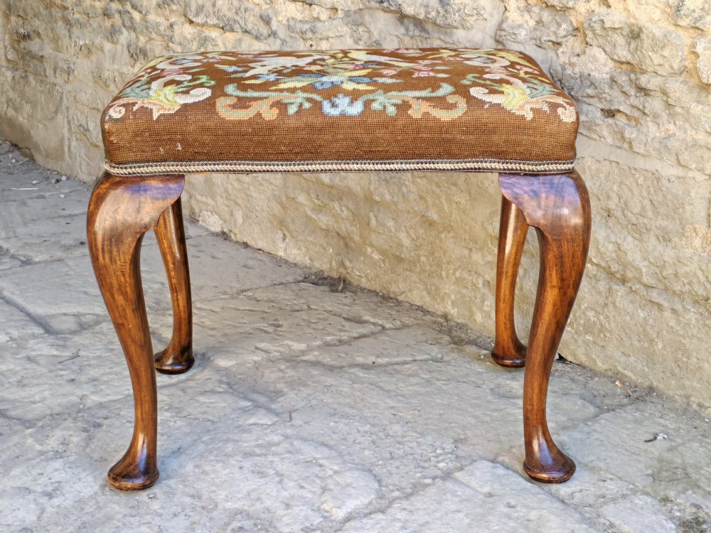 An antique walnut footstool with cabriole legs featuring a brown needlepoint upholstered seat depicting two birds amidst flowers. View IV