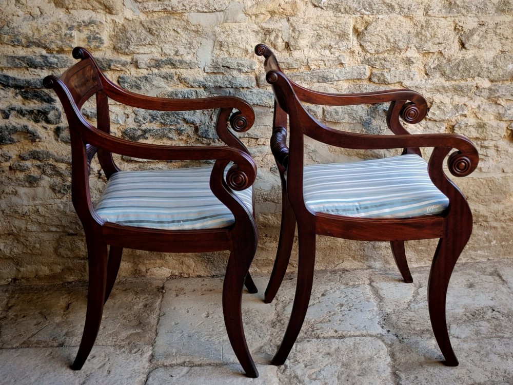 A pair of Regency mahogany carver dining chairs featuring rope-twist back rails, reeded scrolled arms, sabre front legs, and light blue striped upholstered seats. View II