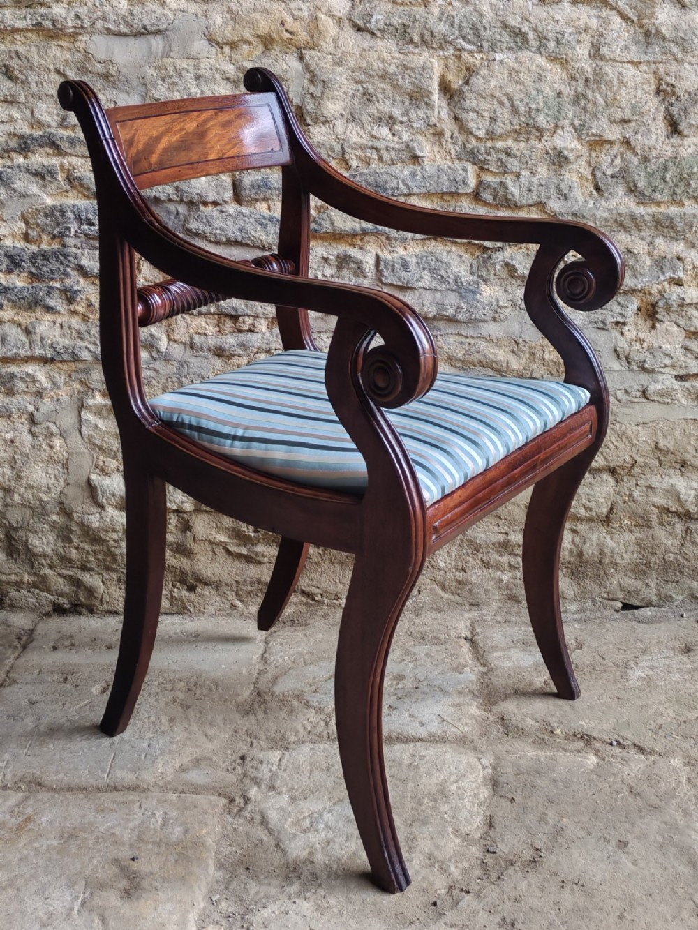 A pair of Regency mahogany carver dining chairs featuring rope-twist back rails, reeded scrolled arms, sabre front legs, and light blue striped upholstered seats. View III