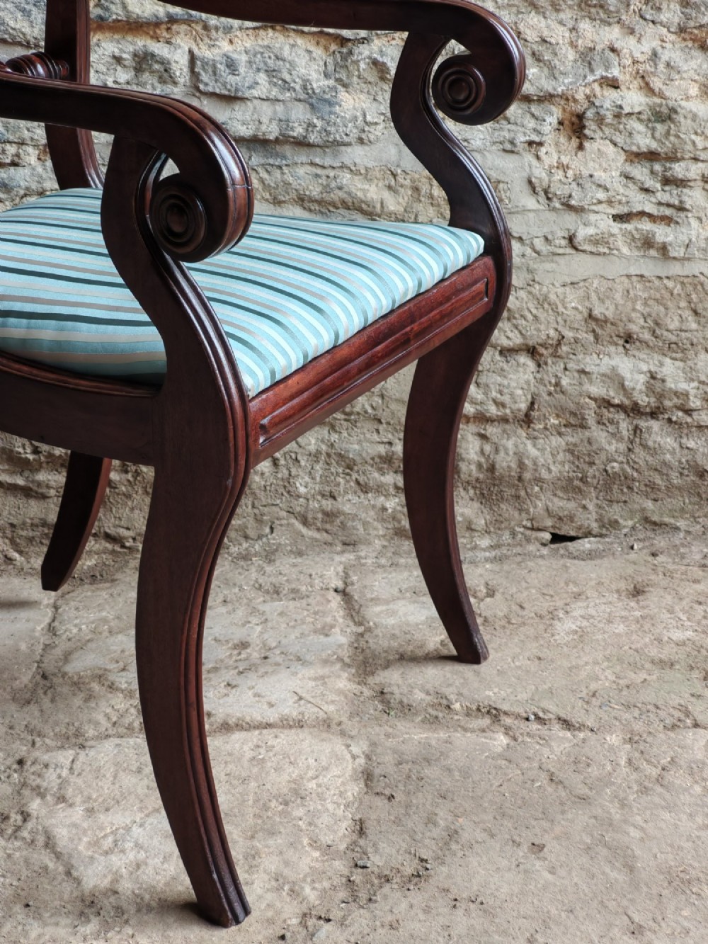 A pair of Regency mahogany carver dining chairs featuring rope-twist back rails, reeded scrolled arms, sabre front legs, and light blue striped upholstered seats. View VI