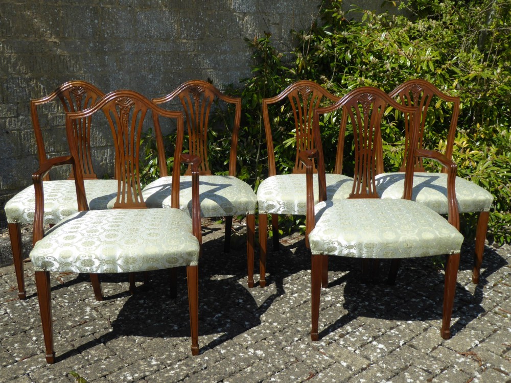 A set of six mahogany dining chairs featuring carved pierced back splats, tapered legs, and pale green patterned upholstery.