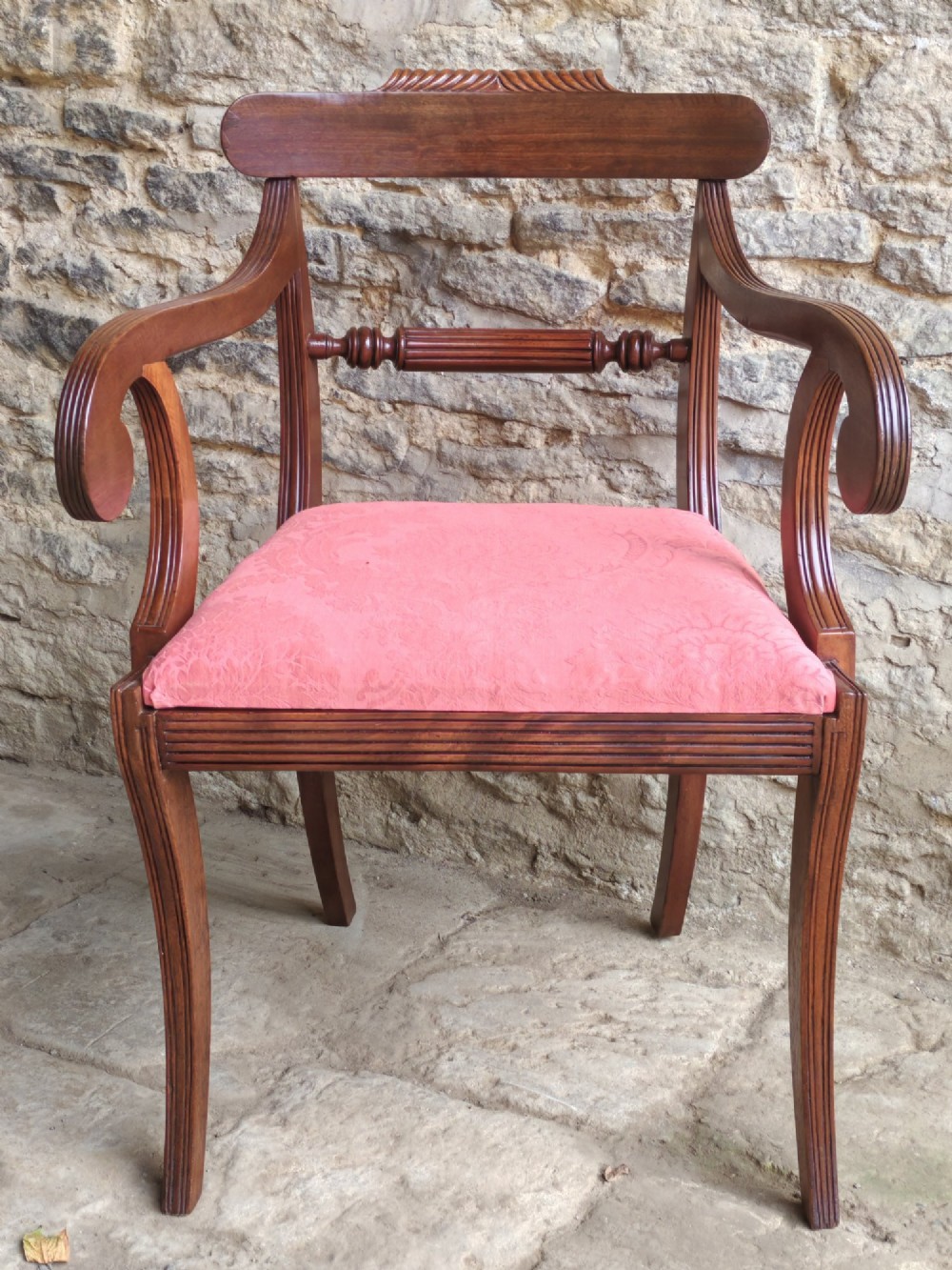 A Regency mahogany carver chair featuring scrolled arms, rope twist carving on the back rail, and a pink upholstered seat.