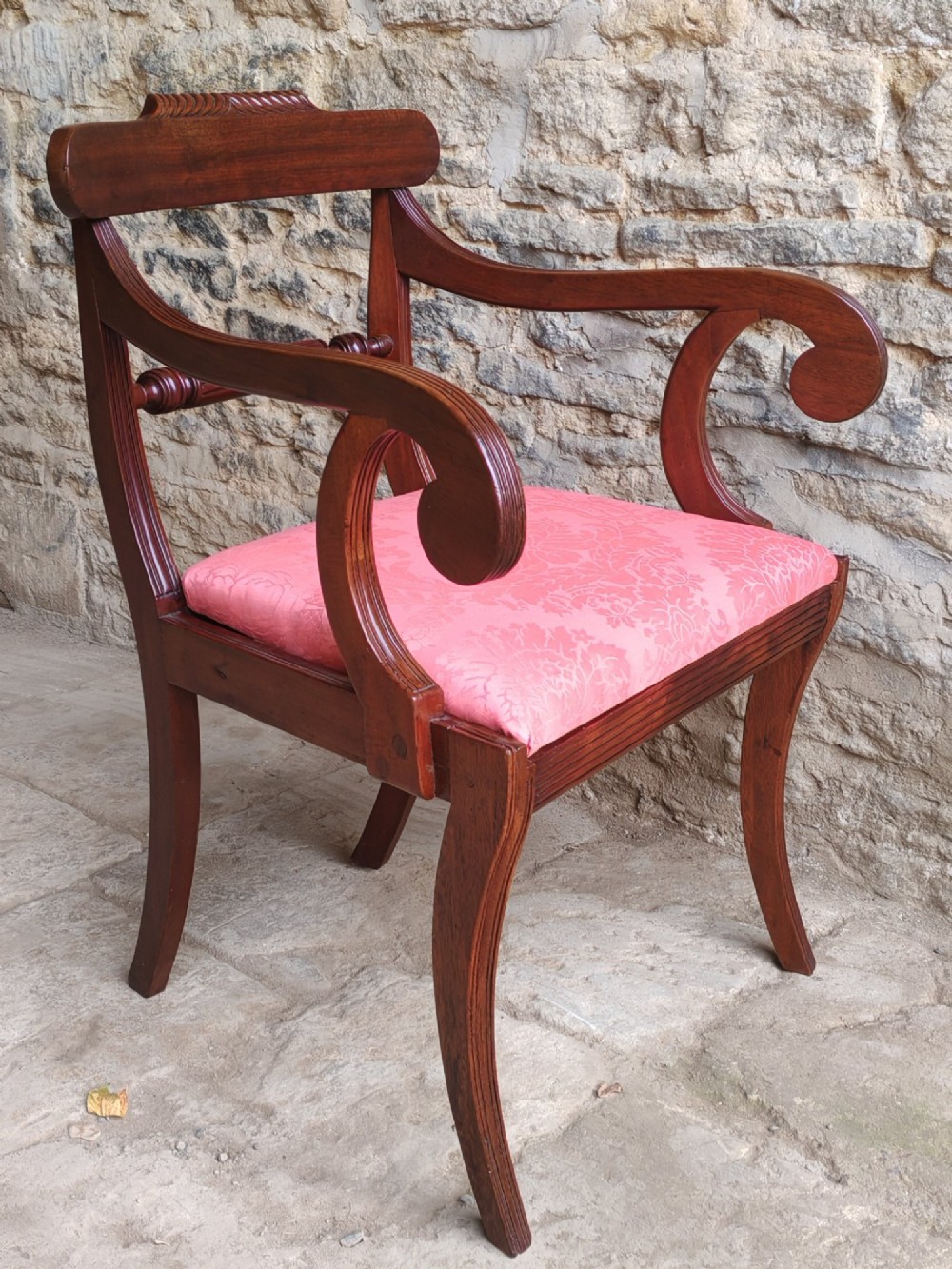 A Regency mahogany carver chair featuring scrolled arms, rope twist carving on the back rail, and a pink upholstered seat. View II