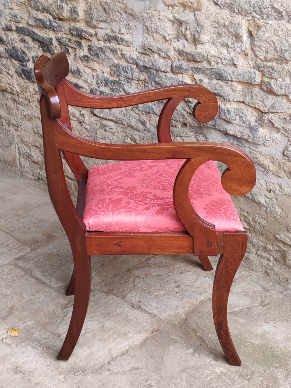 A Regency mahogany carver chair featuring scrolled arms, rope twist carving on the back rail, and a pink upholstered seat. View III