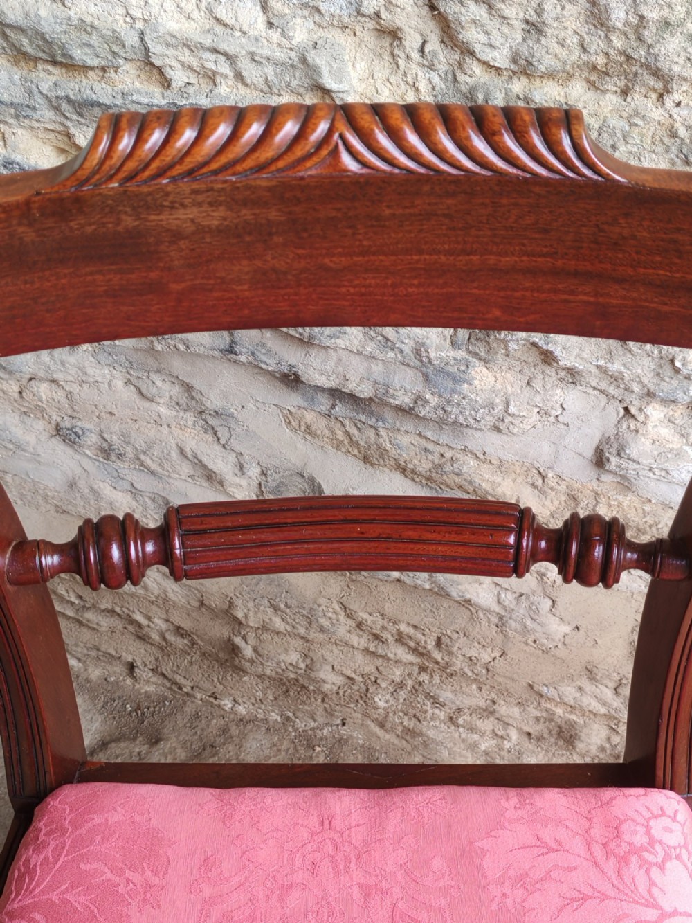 A Regency mahogany carver chair featuring scrolled arms, rope twist carving on the back rail, and a pink upholstered seat. View VII