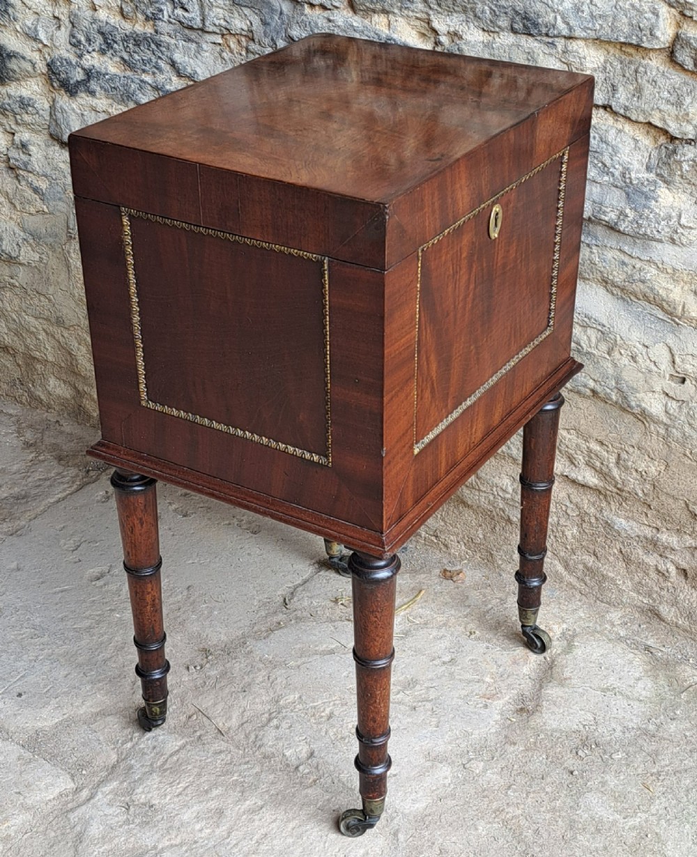 A tall Regency mahogany cellaret with a hinged lid, decorative ormolu beaded borders, a brass keyhole, and turned legs with brass castors. View III