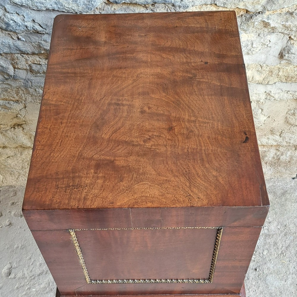 A tall Regency mahogany cellaret with a hinged lid, decorative ormolu beaded borders, a brass keyhole, and turned legs with brass castors. View IV