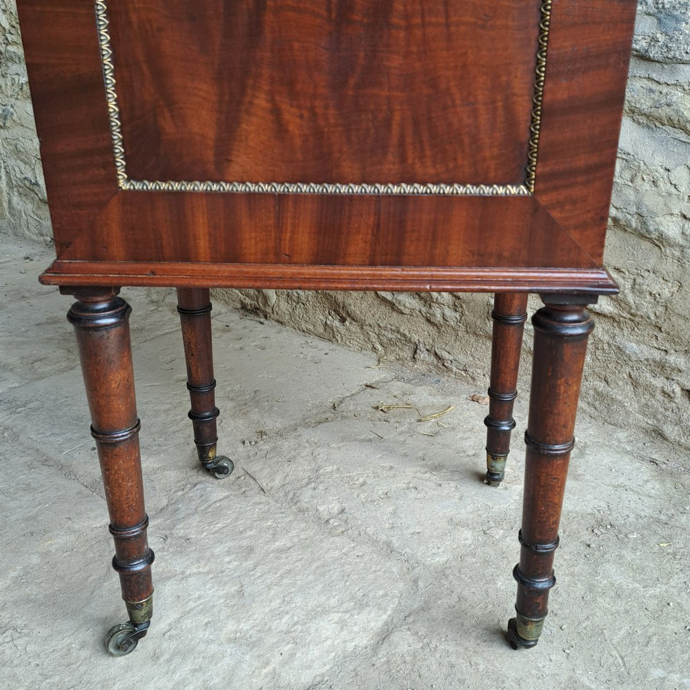A tall Regency mahogany cellaret with a hinged lid, decorative ormolu beaded borders, a brass keyhole, and turned legs with brass castors. View V