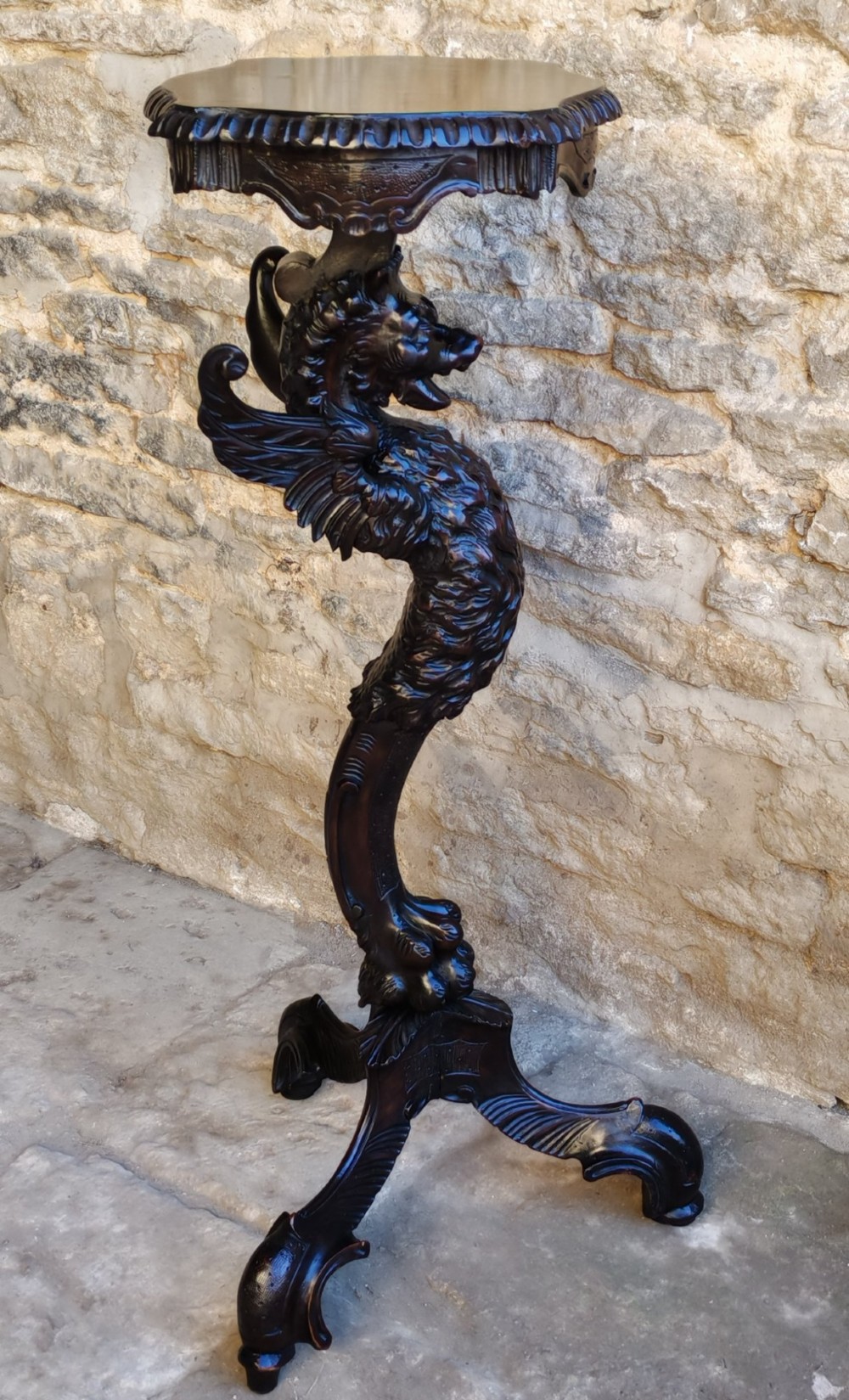 A nineteenth-century dark wood torchere stand featuring a hand-carved dragon support column and a molded circular top on a tripod base.