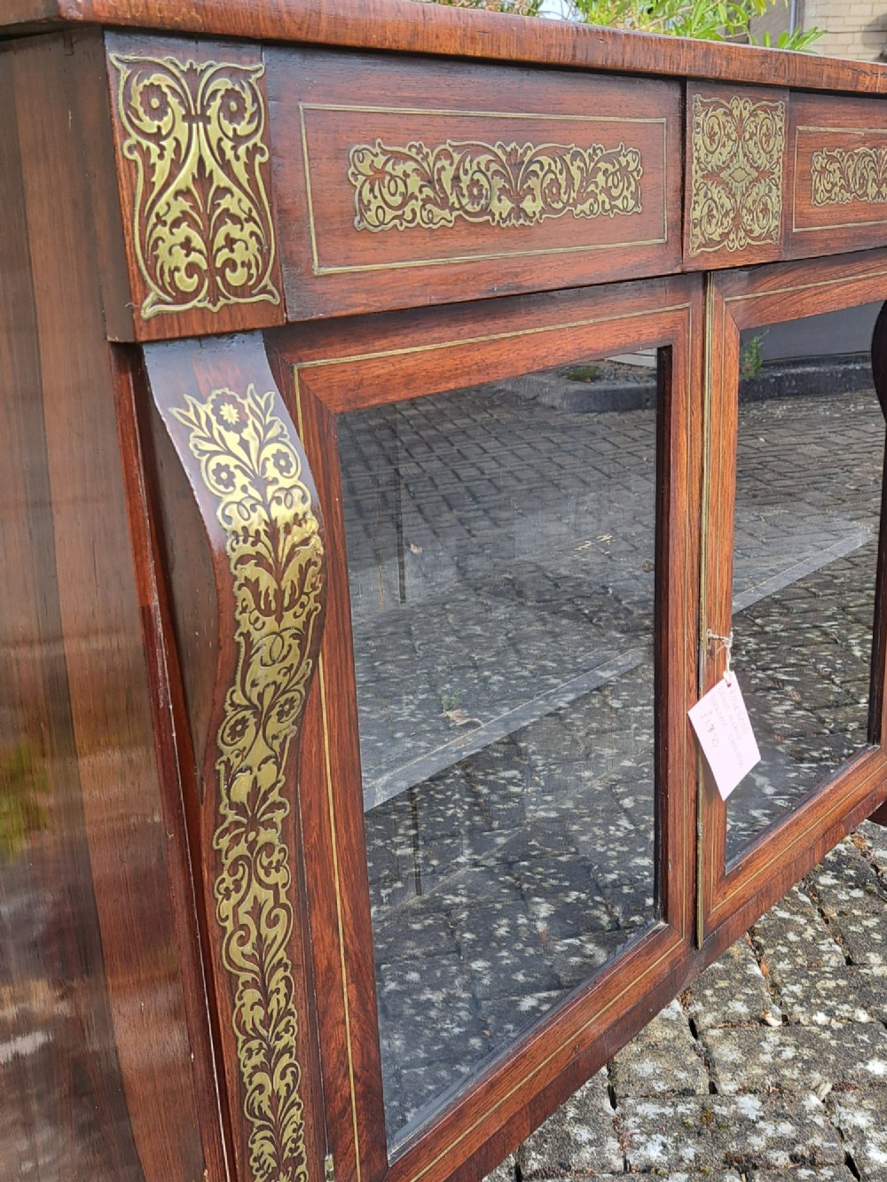 An 1830s rosewood low bookcase featuring twin glazed doors, scroll feet, and foliate brass inlay across the frieze and pilasters. View V