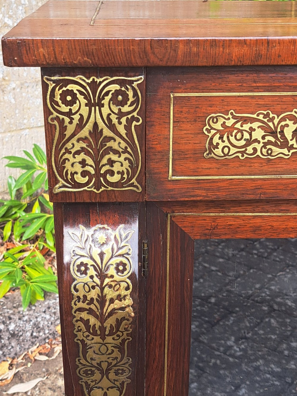 An 1830s rosewood low bookcase featuring twin glazed doors, scroll feet, and foliate brass inlay across the frieze and pilasters. View VI