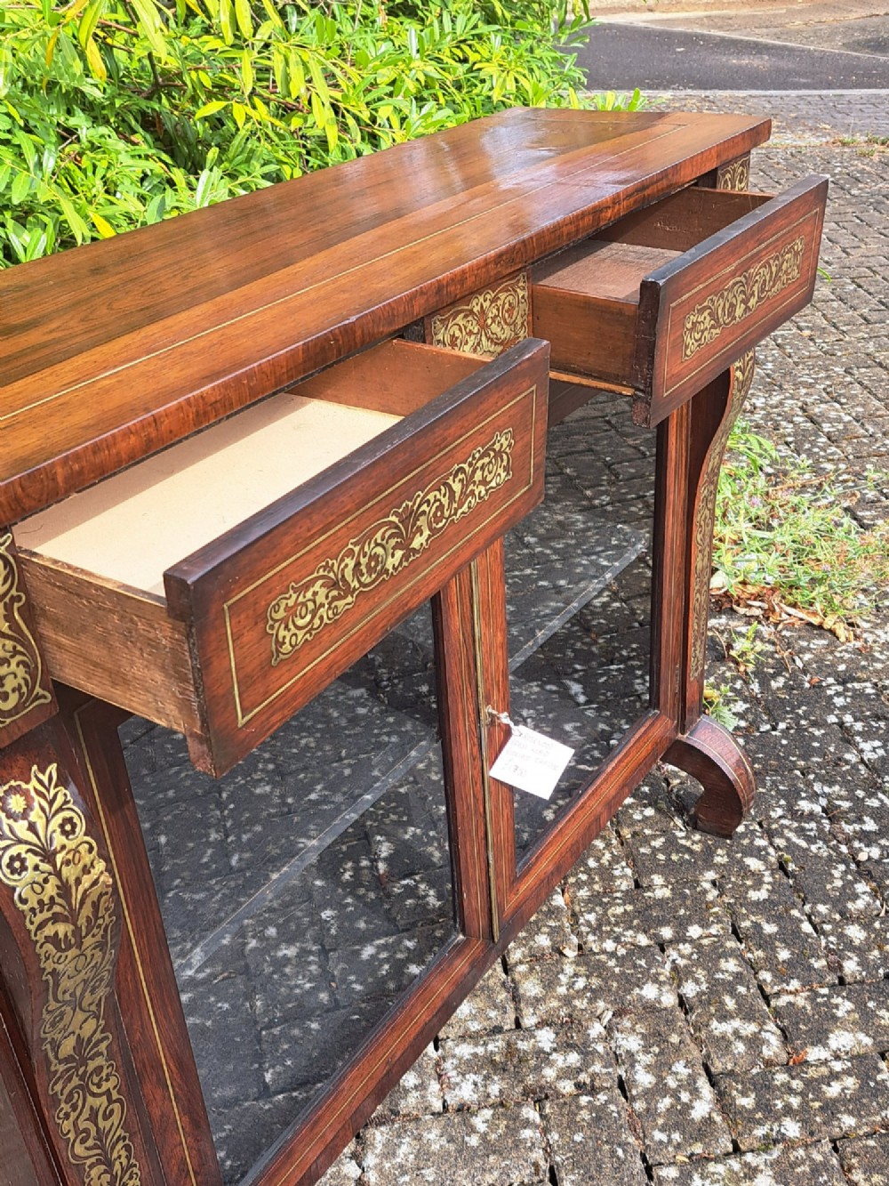An 1830s rosewood low bookcase featuring twin glazed doors, scroll feet, and foliate brass inlay across the frieze and pilasters. View VIII
