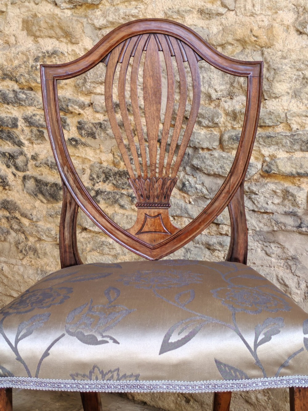 Set of four antique mahogany Hepplewhite dining chairs with carved shield backs and pattern upholstered seats. View V
