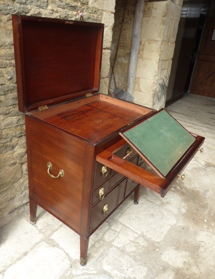An eighteenth-century mahogany campaign chest with an open top lid, side brass handles, and an extended writing slope lined with green baize.