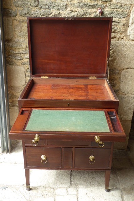 An eighteenth-century mahogany campaign chest with an open top lid, side brass handles, and an extended writing slope lined with green baize. View II